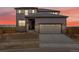 Charming two-story home with a two-car garage, stone accents, and gray siding under a sunset sky at 8809 Sedalia St, Commerce City, CO 80022
