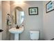 Clean powder room with a pedestal sink, toilet, and decorative artwork at 4100 Albion St # 1509, Denver, CO 80216