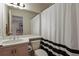 Bright bathroom with a sink, toilet, and a shower featuring a black and white striped curtain at 1503 W Briarwood Ave, Littleton, CO 80120