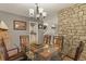 Bright dining room with modern chandelier, glass table, and exposed stone wall at 1503 W Briarwood Ave, Littleton, CO 80120