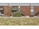 Brick condo building with private exterior staircase and landscaped entry with green bushes in a quiet area at 3663 S Sheridan Blvd # 14, Denver, CO 80235