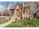 Quaint brick home featuring mature landscaping, a cozy front porch, and a well-manicured lawn at 2088 Kearney St, Denver, CO 80207