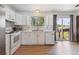 Bright white kitchen with stainless steel appliances, wood floors, and a sliding glass door to the backyard at 5372 E 108Th Pl, Thornton, CO 80233