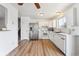 Inviting kitchen with white cabinets, stainless steel appliances, wood-look floors and adjacent stairs to an upper level at 5372 E 108Th Pl, Thornton, CO 80233