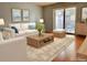 Bright living room featuring a white sofa, wood coffee table, area rug, and access to a balcony at 7755 E Quincy Ave # 203A6, Denver, CO 80237