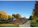 Community playground with play structures, swings and slides among fall foliage at 7755 E Quincy Ave # 203A6, Denver, CO 80237