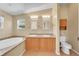 Bright bathroom featuring a soaking tub, double sinks, oak cabinets, and modern fixtures at 7870 Sunflower Green # 151, Frederick, CO 80530