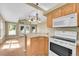 Open kitchen with wood cabinets, white appliances, and a connecting living space at 7870 Sunflower Green # 151, Frederick, CO 80530