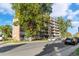 View of the apartment building with balconies, mature trees, and street parking at 4801 E 9Th Ave # 209S, Denver, CO 80220