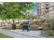 Outdoor grilling area with BBQ grill and seating near mature landscaping and tall apartment building at 4801 E 9Th Ave # 209S, Denver, CO 80220