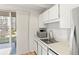 This bright and functional kitchen features white cabinets and appliances with view to a patio at 4801 E 9Th Ave # 209S, Denver, CO 80220