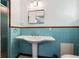Retro bathroom with blue tile, pedestal sink, mirrored medicine cabinet, and separate shower stall at 100 Dudley St, Lakewood, CO 80226