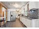Charming kitchen featuring white cabinets, stainless steel appliances, mosaic backsplash, and tile flooring at 100 Dudley St, Lakewood, CO 80226