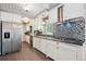 Modern kitchen featuring white cabinets, stainless steel appliances, mosaic backsplash, and tile flooring at 100 Dudley St, Lakewood, CO 80226