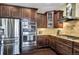 Gourmet kitchen with stainless steel appliances, dark wood cabinets, granite countertops, and tiled backsplash at 22527 E Layton Cir, Aurora, CO 80015