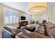Cozy living room featuring a fireplace, plush brown leather seating, and large windows with plantation shutters at 22527 E Layton Cir, Aurora, CO 80015