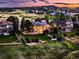Aerial view of a home at sunset, showcasing lush landscaping, mature trees, and picturesque surroundings at 5149 Raintree Dr, Parker, CO 80134