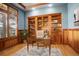 Stylish home office with custom built-ins, wood paneling, hardwood floors and large window with shutters at 5149 Raintree Dr, Parker, CO 80134