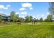 A beautiful park-like backyard with playground, bench seating, mature trees, and a lawn at 708 Teal Cir, Longmont, CO 80503