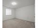 A bright bedroom with neutral carpeting, white walls, a large window, and a door to the hallway at 708 Teal Cir, Longmont, CO 80503