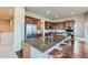An open kitchen is equipped with a large granite island, stainless steel refrigerator, and hardwood floors at 6216 E 135Th Ave, Thornton, CO 80602