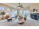 Spacious living room with high ceilings, a ceiling fan, large windows, and a cozy fireplace, perfect for relaxation at 6216 E 135Th Ave, Thornton, CO 80602
