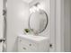 Modern bathroom with a round mirror, elegant vanity, and stylish globe lighting fixtures at 117 S Pierce St, Lakewood, CO 80226