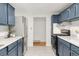 Updated kitchen features stainless steel appliances and stylish blue cabinets with white countertops and backsplash at 117 S Pierce St, Lakewood, CO 80226