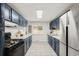 Well-lit kitchen featuring stainless steel appliances, stylish blue cabinets, and bright white countertops with window view at 117 S Pierce St, Lakewood, CO 80226