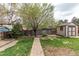Well-maintained backyard with a shed, mature trees, and brick pathway at 17882 E Wyoming Pl, Aurora, CO 80017
