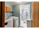 Functional laundry room with white appliances, shelf and views of updated bathroom at 17882 E Wyoming Pl, Aurora, CO 80017