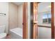 Bright bathroom featuring a tub, tiled walls, and a view into a sunlit room with large windows at 3191 Bittersweet Ln, Evergreen, CO 80439