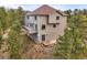 Back of home with deck, patio, and surrounding trees on a hillside lot at 3191 Bittersweet Ln, Evergreen, CO 80439