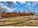 Fenced backyard offering privacy and security, with a grassy lawn and mature trees at 1177 Jamaica St, Aurora, CO 80010