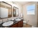 Bathroom featuring double sinks, dark wood cabinets, and a framed mirror over each sink at 11213 Colony Cir, Broomfield, CO 80021