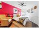 Stylish bedroom with vibrant red accent wall, large window, and a comfortable wicker chair at 4878 E Kentucky Ave # B, Denver, CO 80246