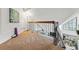 Upstairs loft with railing and a view into the living room with large windows at 4878 E Kentucky Ave # B, Denver, CO 80246