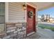 Close-up of a stylish red front door with a wreath, set in a stone entryway with a welcome mat at 10152 Xanadu St, Commerce City, CO 80022