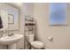 Powder bathroom with a decorative framed mirror, metal shelving, and a pedestal sink at 4724 S Wenatchee Cir, Aurora, CO 80015