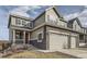 Two story home with grey siding and stone accents, a two car garage, and covered porch at 4724 S Wenatchee Cir, Aurora, CO 80015