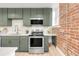 Well-appointed kitchen with stainless steel appliances, green cabinets and exposed brick at 1210 E Colfax Ave # 104, Denver, CO 80218