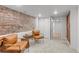 Relaxing room with exposed brick, comfortable seating, and convenient access to a closet and hallway at 1210 E Colfax Ave # 104, Denver, CO 80218