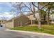 View of a townhome showing an attached garage, side door, and mature trees on a grassy lot at 5316 S Jellison St, Littleton, CO 80123