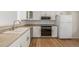 Well-lit kitchen featuring white cabinets, modern appliances, and stylish hardwood floors at 5316 S Jellison St, Littleton, CO 80123