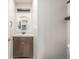 Stylish powder room with a wood vanity, round mirror, and floating shelves at 5316 S Jellison St, Littleton, CO 80123