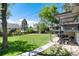 Expansive backyard with lush green lawn, mature trees, and a concrete walkway at 4545 S Lipan Ct, Englewood, CO 80110