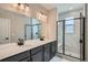 Modern bathroom featuring double sink vanity, walk-in shower with a glass door, and marble-style floors at 8321 Mount Kataka St, Littleton, CO 80125