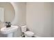 Clean, modern powder room featuring a pedestal sink, round mirror, and neutral wall color at 8321 Mount Kataka St, Littleton, CO 80125