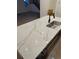 This kitchen island features a white countertop with light tan veining, stainless steel sink and black faucet at 5626 W 142Nd Ave, Broomfield, CO 80020