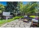 Lush backyard with mature trees, stone patio, hot tub, and cozy seating area with soft cushions at 1278 Dexter St, Denver, CO 80220